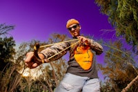 a man holding a bow and arrow in the woods