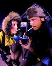 a man and a woman smoking a cigarette next to a parking meter