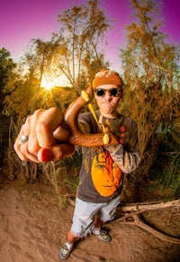 a man with a hat and sunglasses is holding a stick in his hand