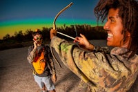 a man with dreadlocks holding a bow and arrow